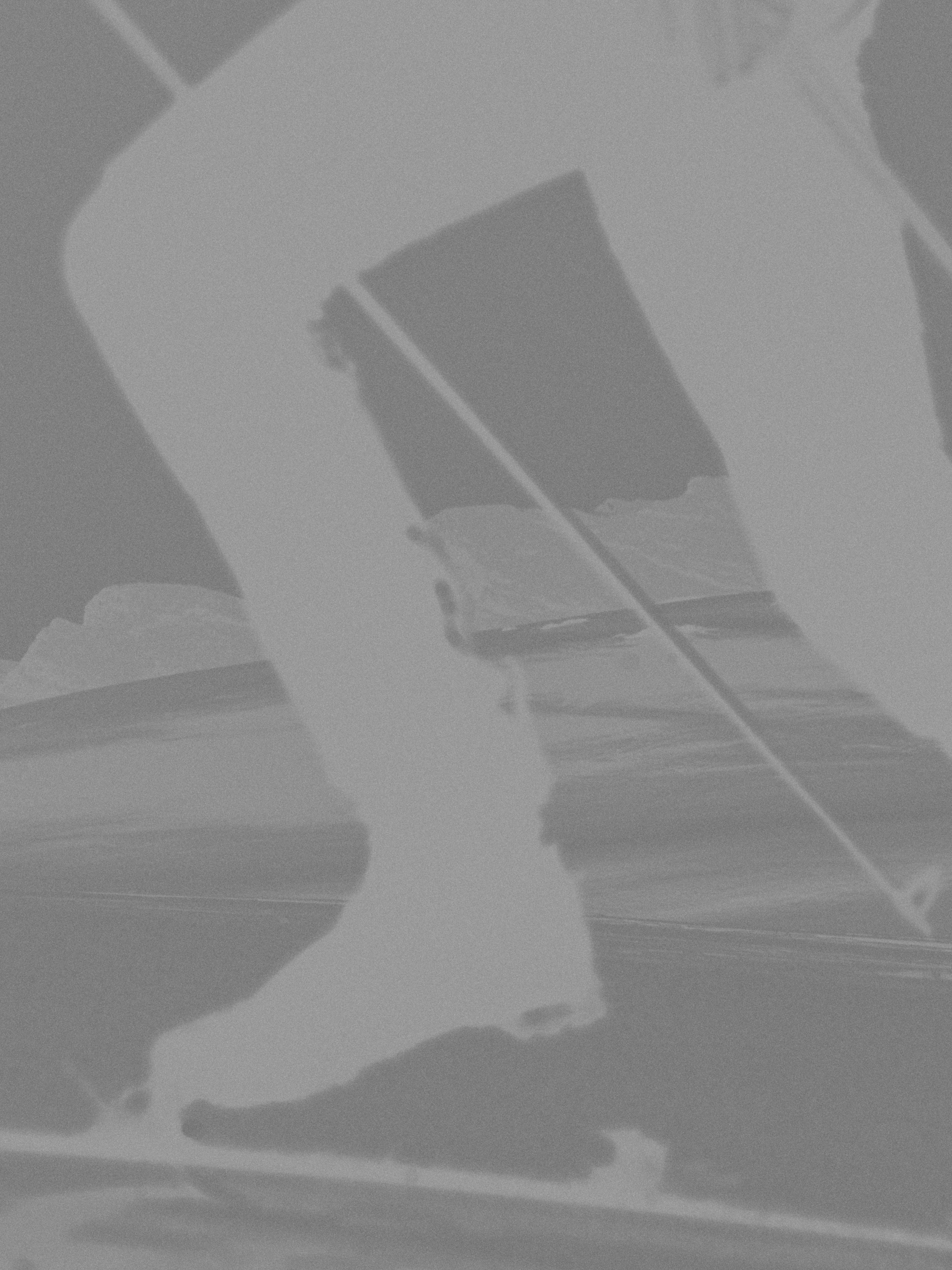 A monochrome, high-contrast artistic photograph showing a close-up of a person's legs and feet in motion, with a ski pole visible against a dark, painterly background.