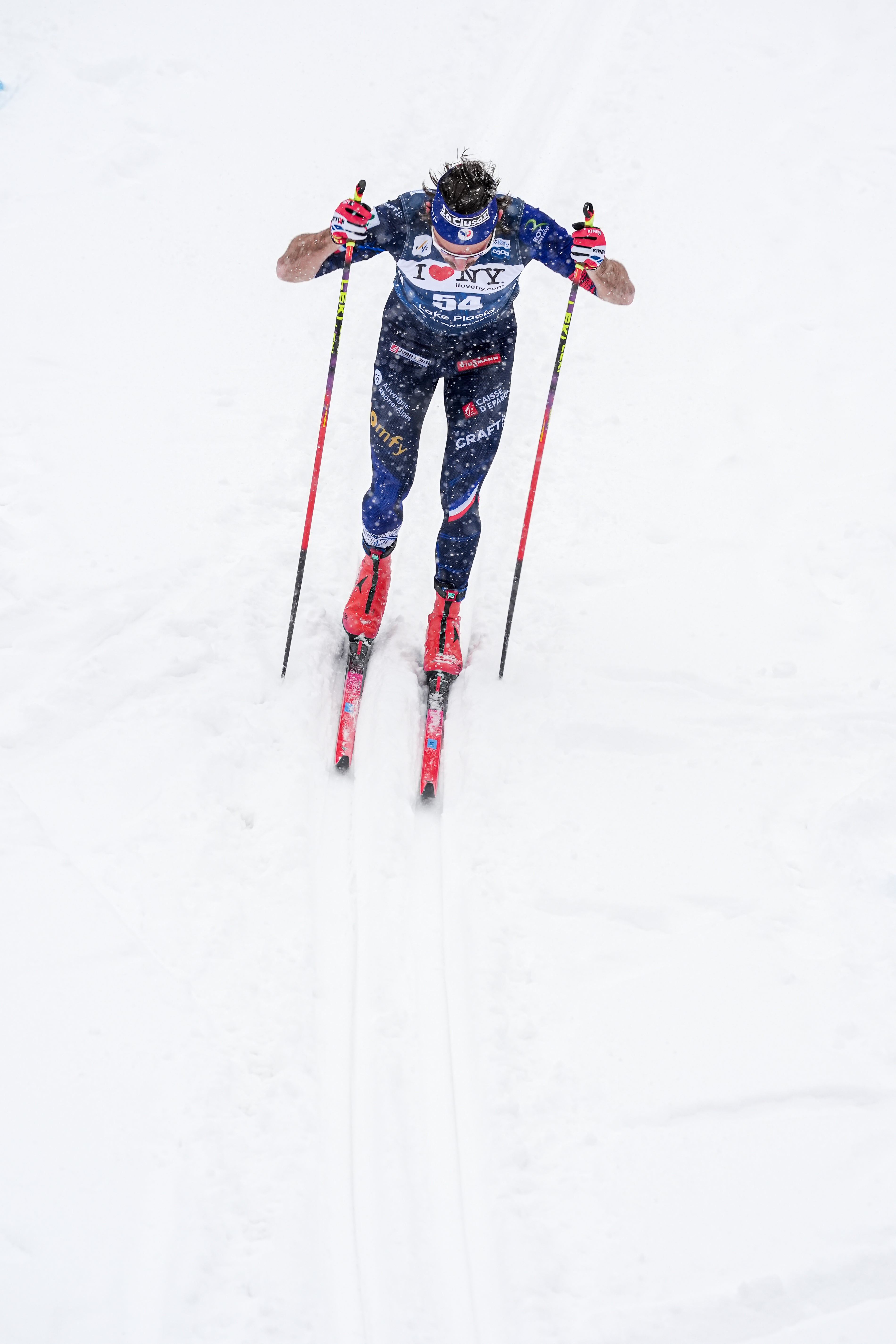 Hugo Lapalus  in a blue and white patterned racing suit with red ski boots and poles, captured skating on a snowy slope.