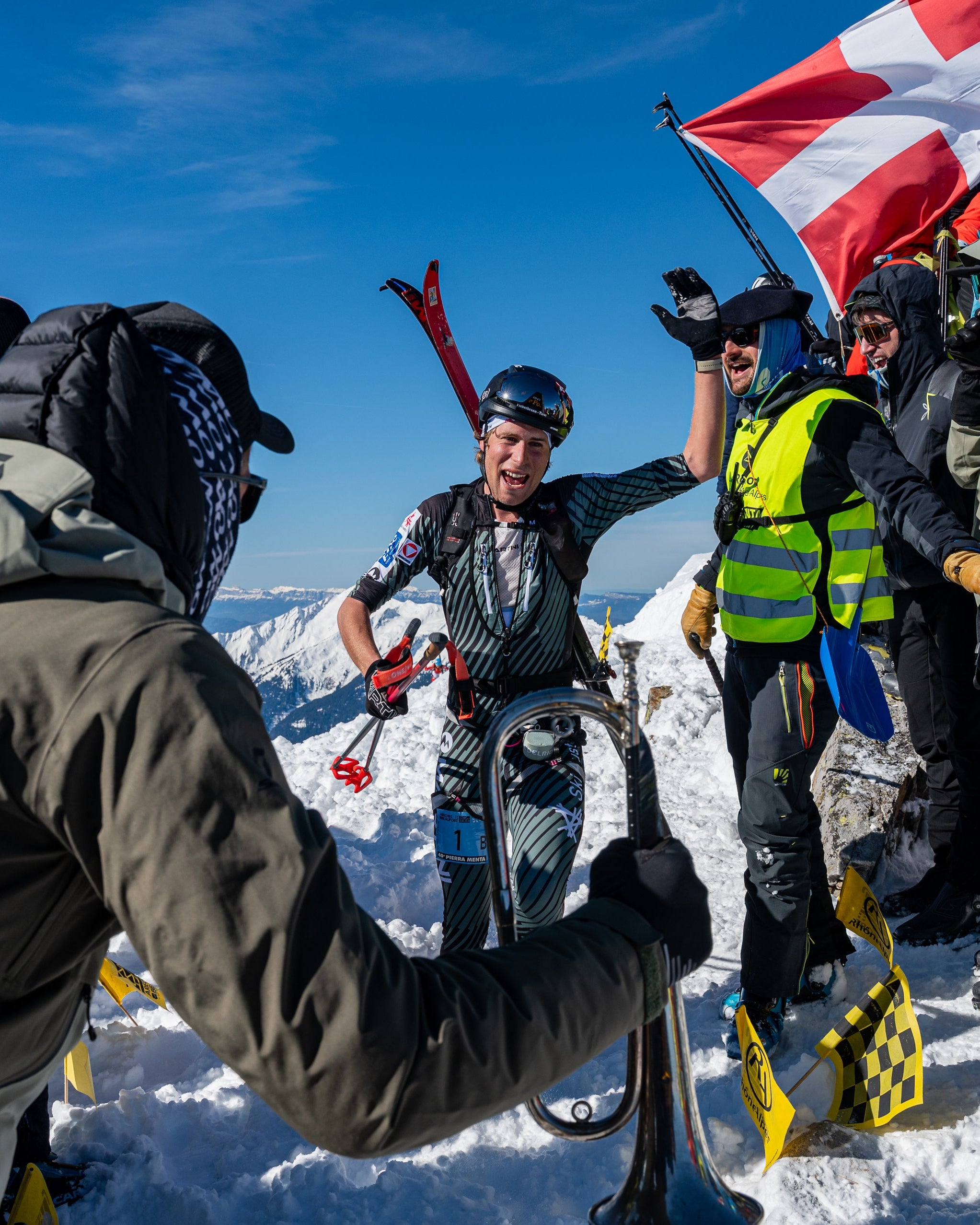 A group of skiers and snowboarders standing in a snowy mountain cheering up for Nils Oberauer during a race.