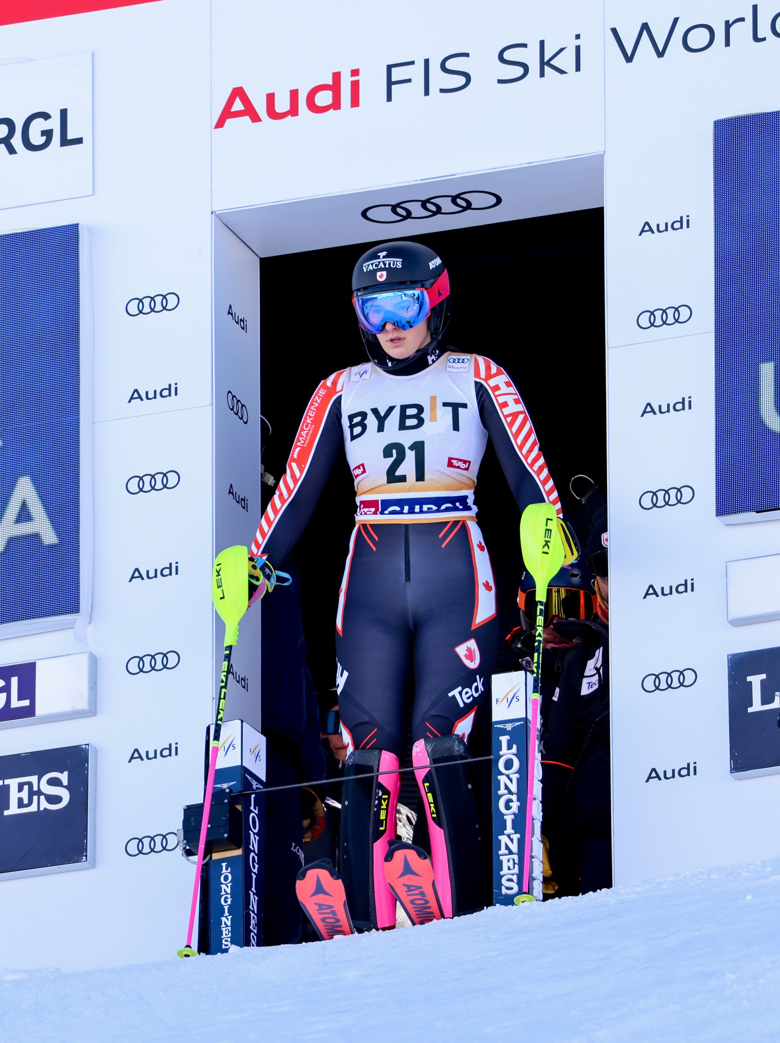Ali Nullmeyer in a black, white, and red racing suit stands in the starting gate at the Audi FIS Ski World Cup.