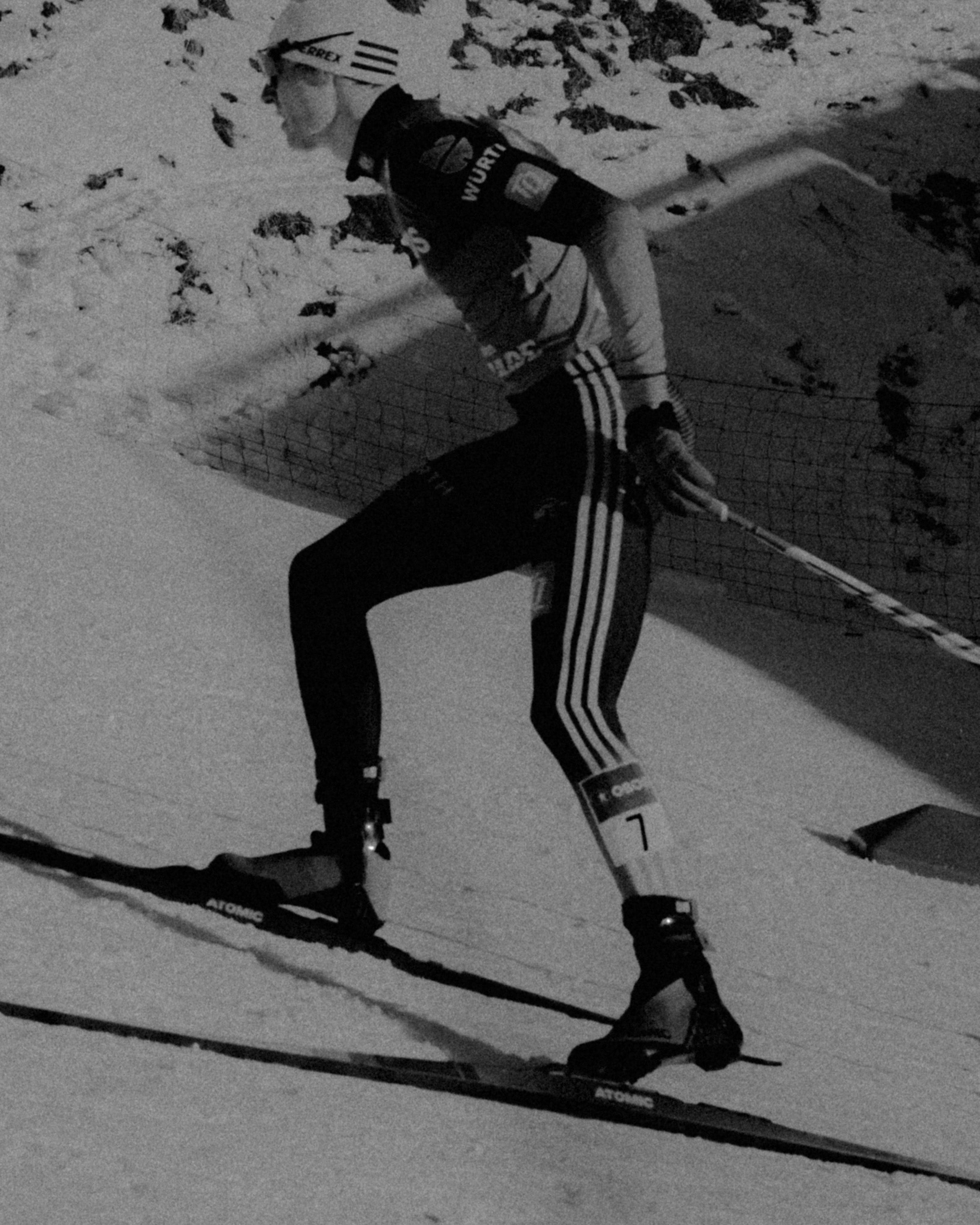 A black and white action shot of Vinzenz Geiger in motion on a snowy mountain slope.