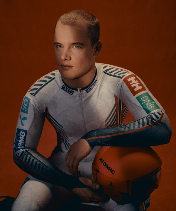 Fredrik Moller in a white, blue, and orange F1 team racing suit holding an orange helmet against a solid dark orange background. Visible sponsor logos include Helly Hansen, DN6 and PMW.