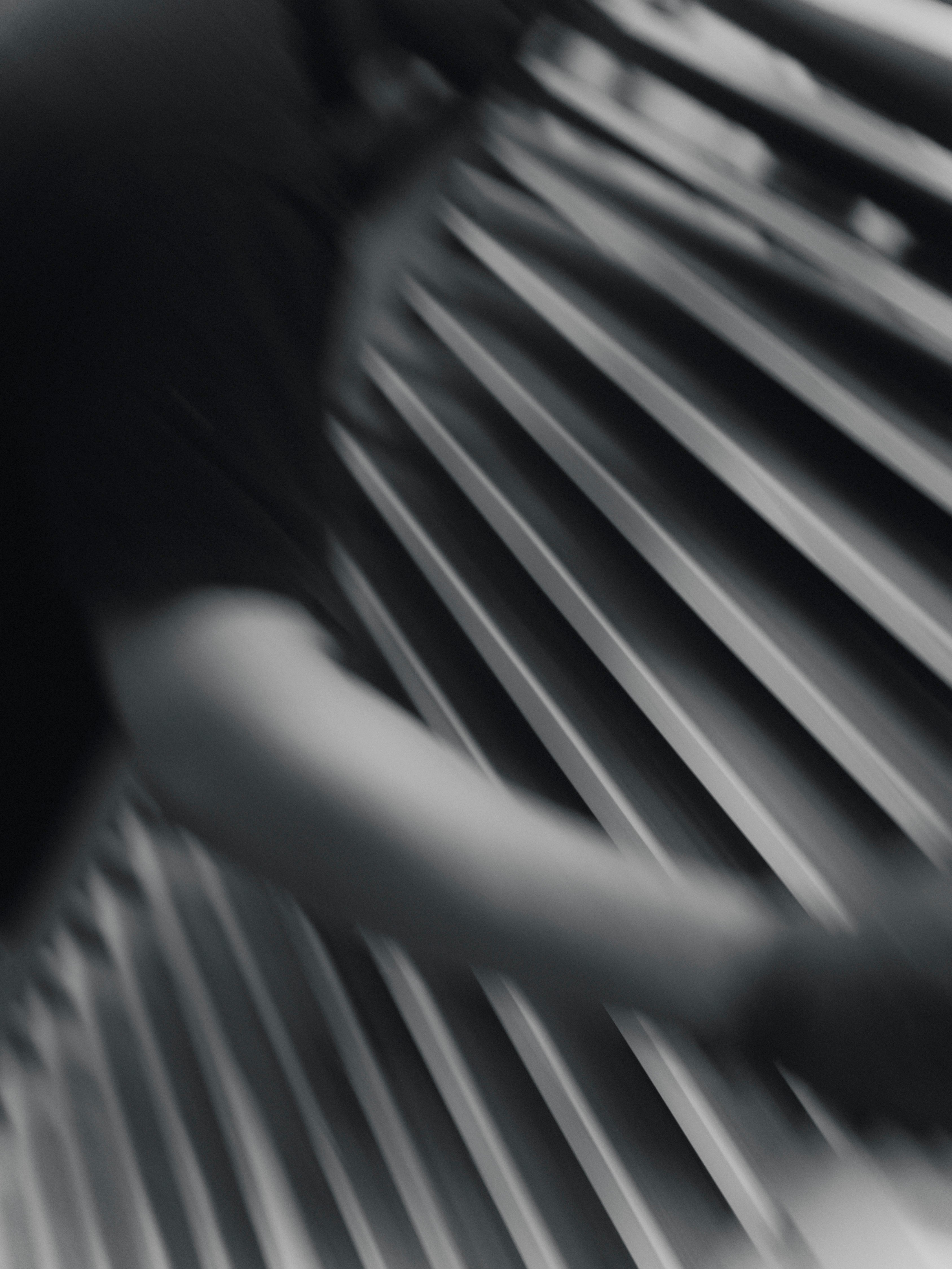 Black and white abstract photograph showing a blurred human arm and torso in motion against diagonal wooden slats.