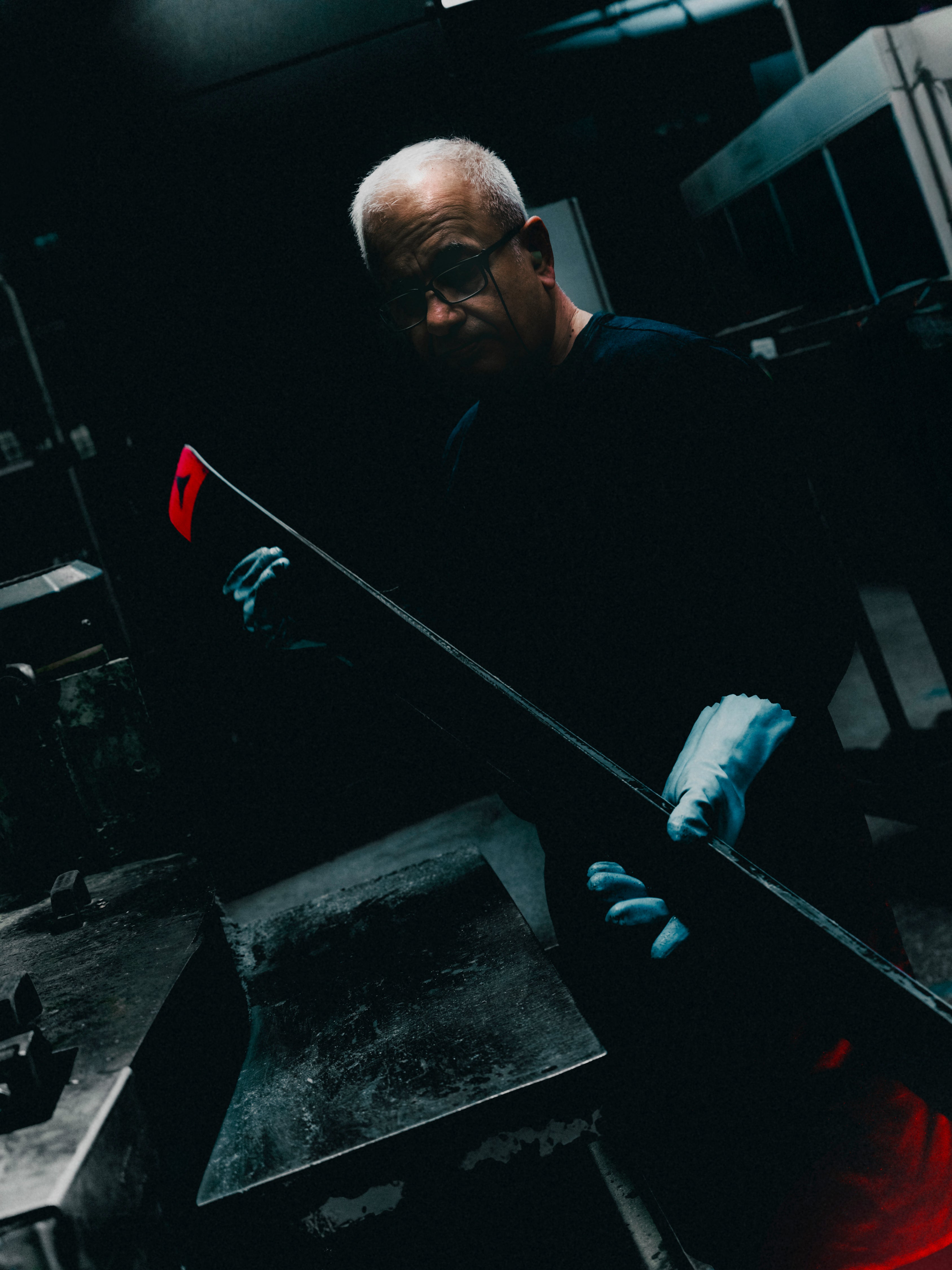 A factory worker wearing gloves and glasses holds a ski in the Atomic Factory. 