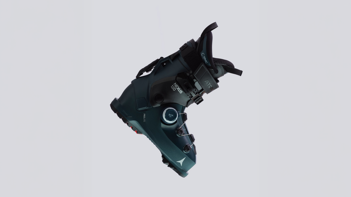 A single ski boot shown floating against a plain light gray studio background. The boot is predominantly dark teal and black with small white and silver details, including visible 'Mizuno' branding and model text.