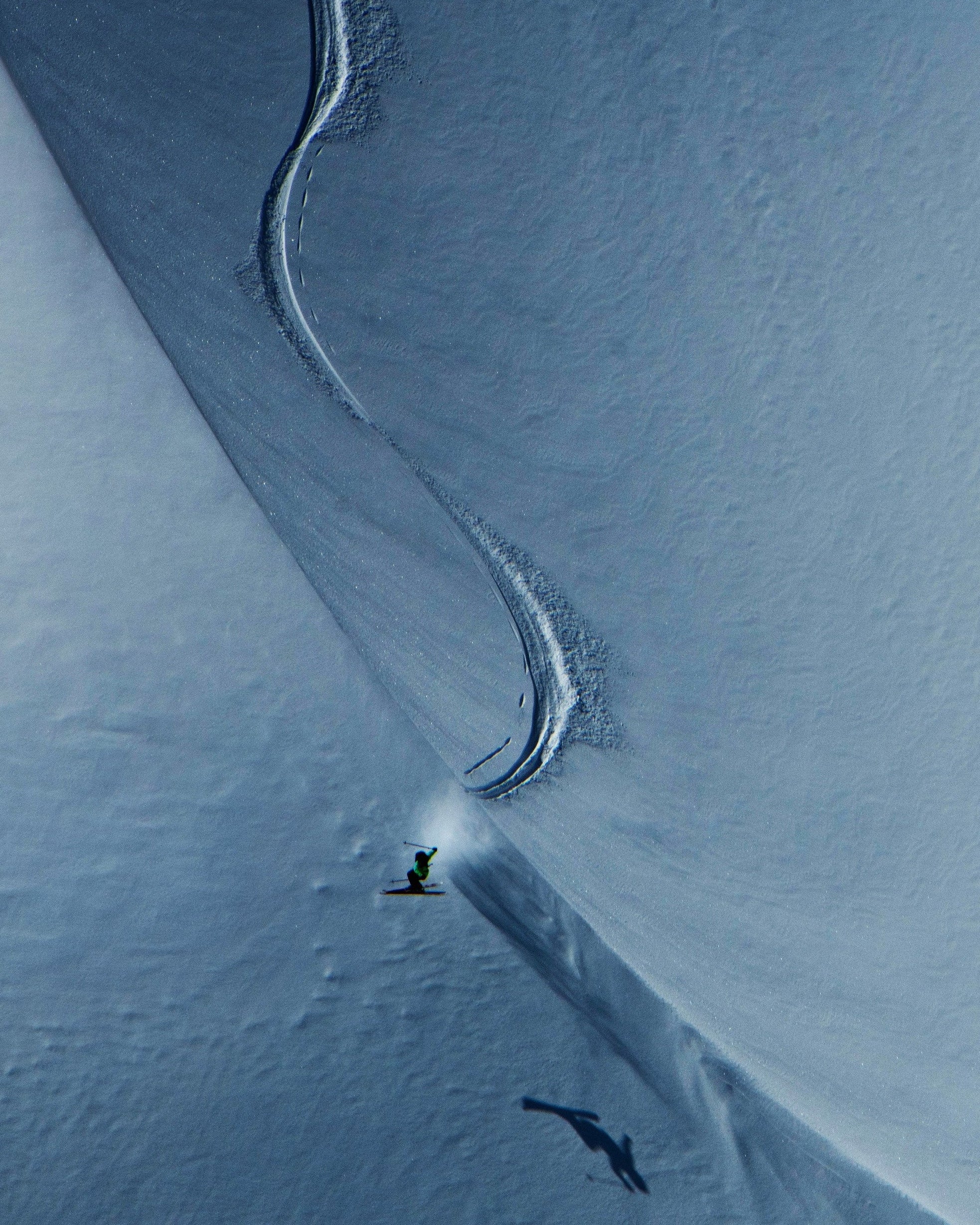 Aerial view of a snowy mountain slope with Sage Cattabriga dropping in the middle.